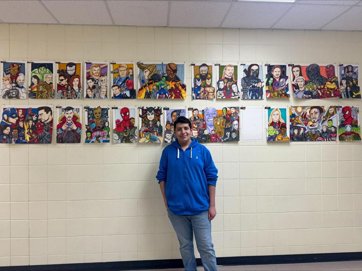 Junior Joel Roman standing by his drawings of the Marvel Cinematic Universe.